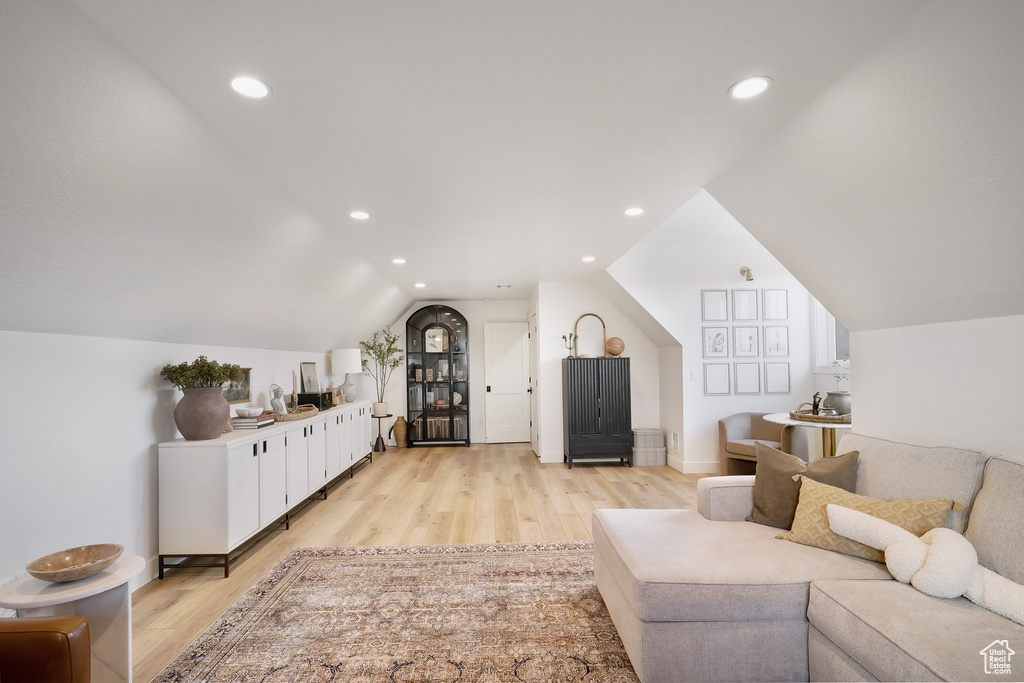 Living room featuring light wood finished floors, lofted ceiling, and recessed lighting