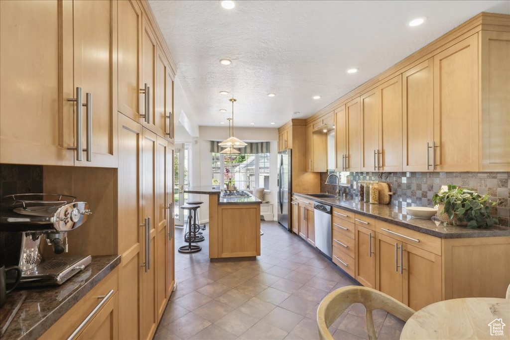 Kitchen featuring a sink, appliances with stainless steel finishes, decorative backsplash, a kitchen breakfast bar, and recessed lighting