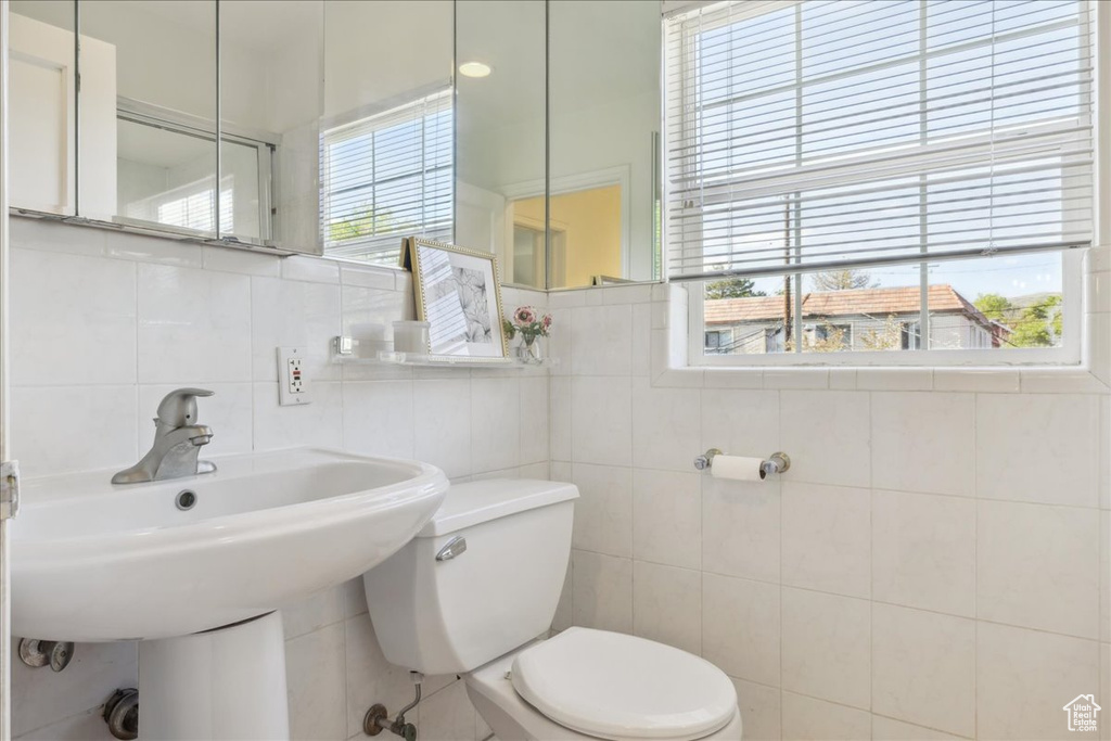 Bathroom featuring tile walls and toilet