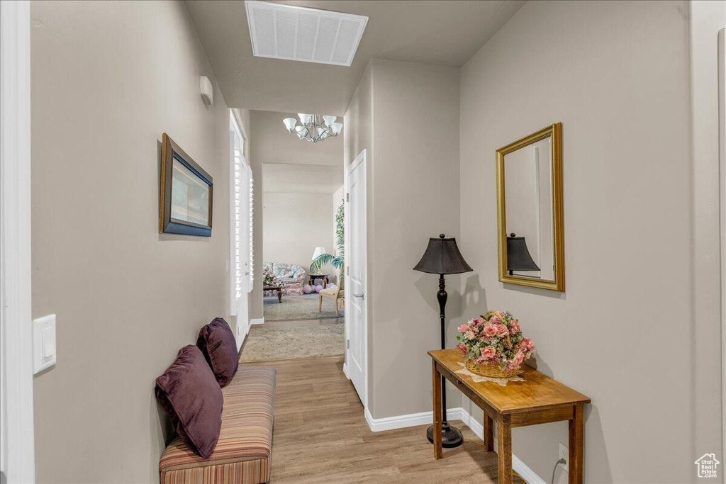 Hall with a chandelier, light wood-style flooring, and baseboards