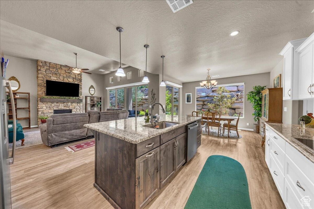 Kitchen with a sink, dishwasher, light wood-style flooring, white cabinets, and dark brown cabinets