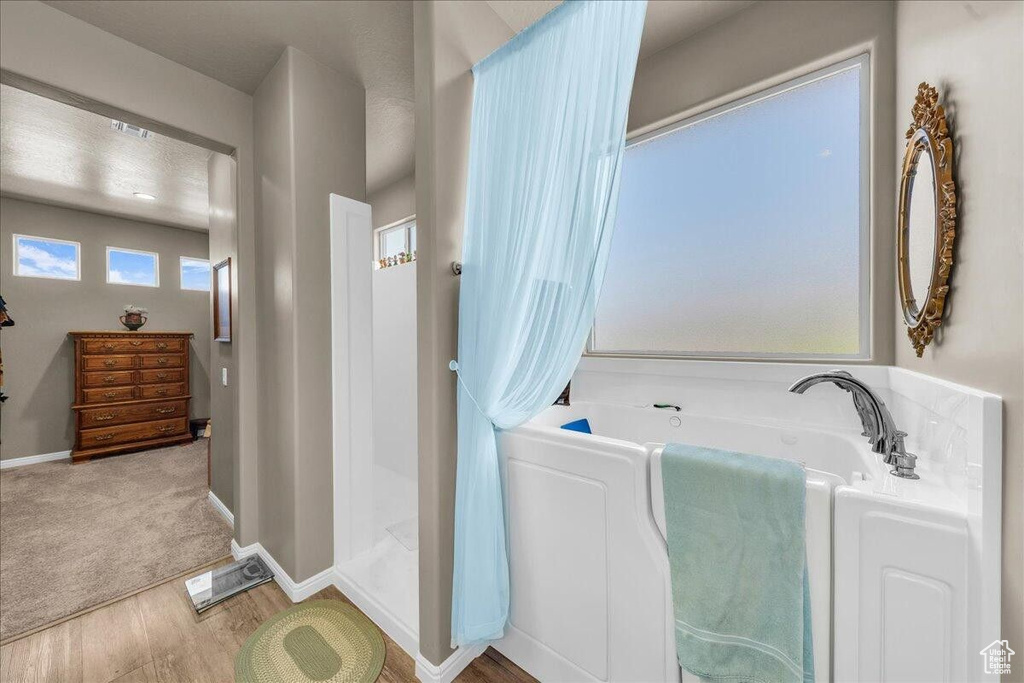 Bathroom with wood finished floors, a bath, and baseboards