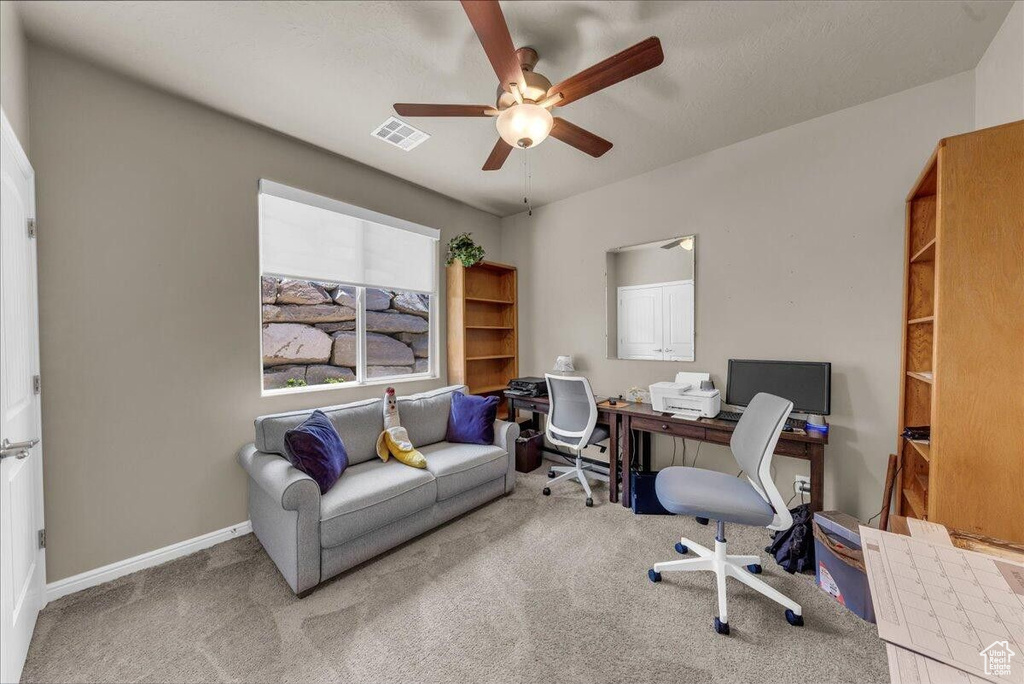 Carpeted home office featuring a ceiling fan and baseboards