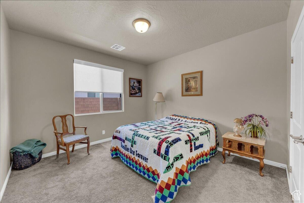 Carpeted bedroom featuring baseboards and a textured ceiling