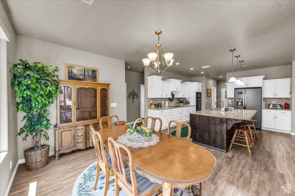 Dining room with light wood finished floors, a chandelier, baseboards, and recessed lighting
