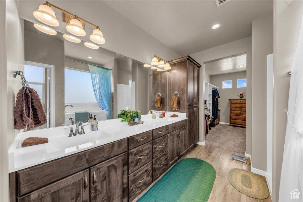 Full bathroom with wood finished floors, double vanity, and baseboards