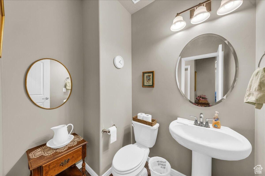 Bathroom featuring toilet, a sink, and baseboards