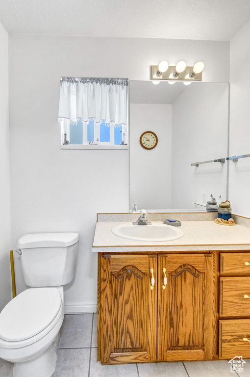 Half bathroom featuring tile patterned flooring, vanity, and toilet