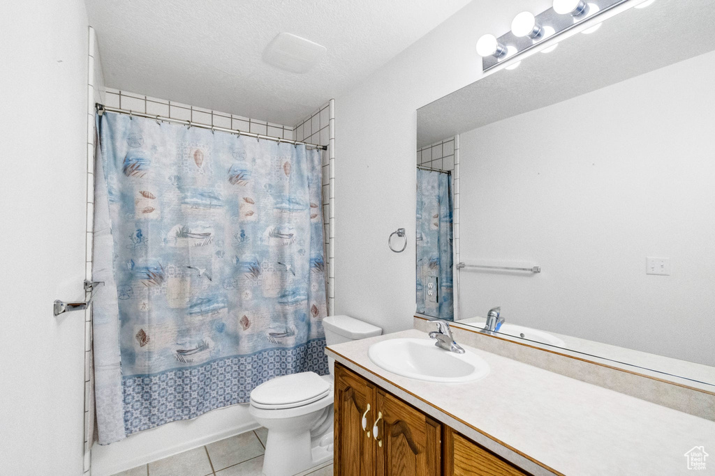 Full bath with toilet, tile patterned flooring, vanity, and shower / bath combo