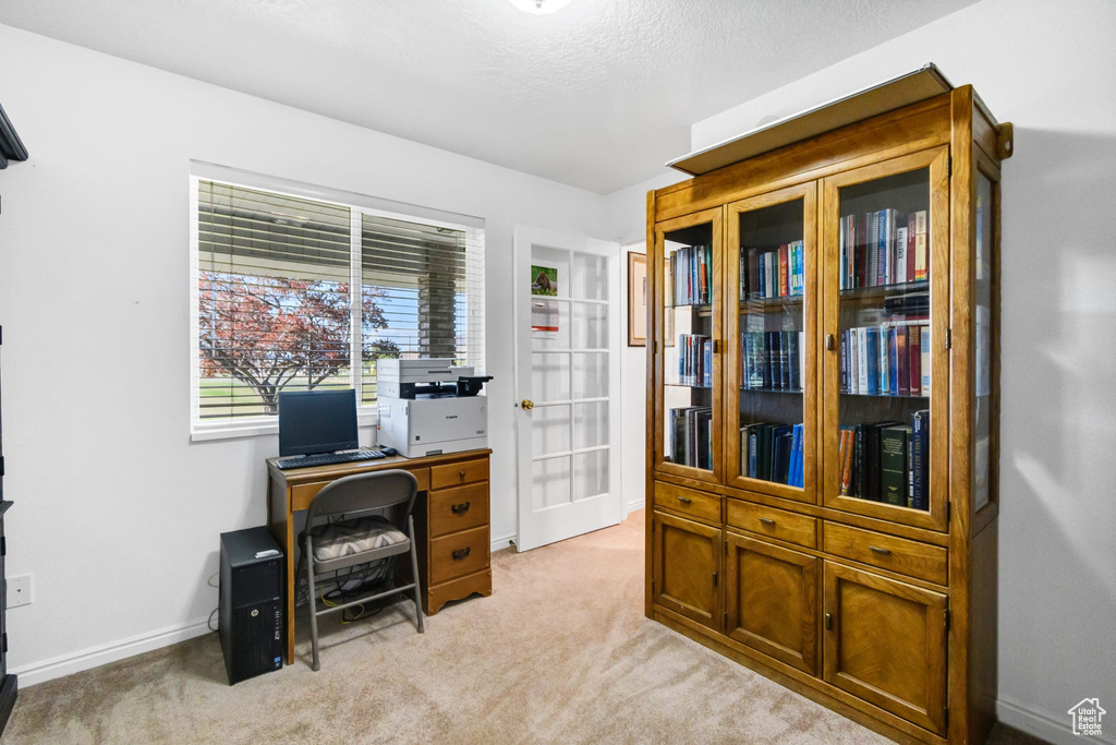 Home office featuring light carpet, baseboards, and french doors