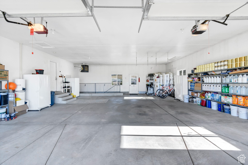 Garage with a garage door opener and freestanding refrigerator