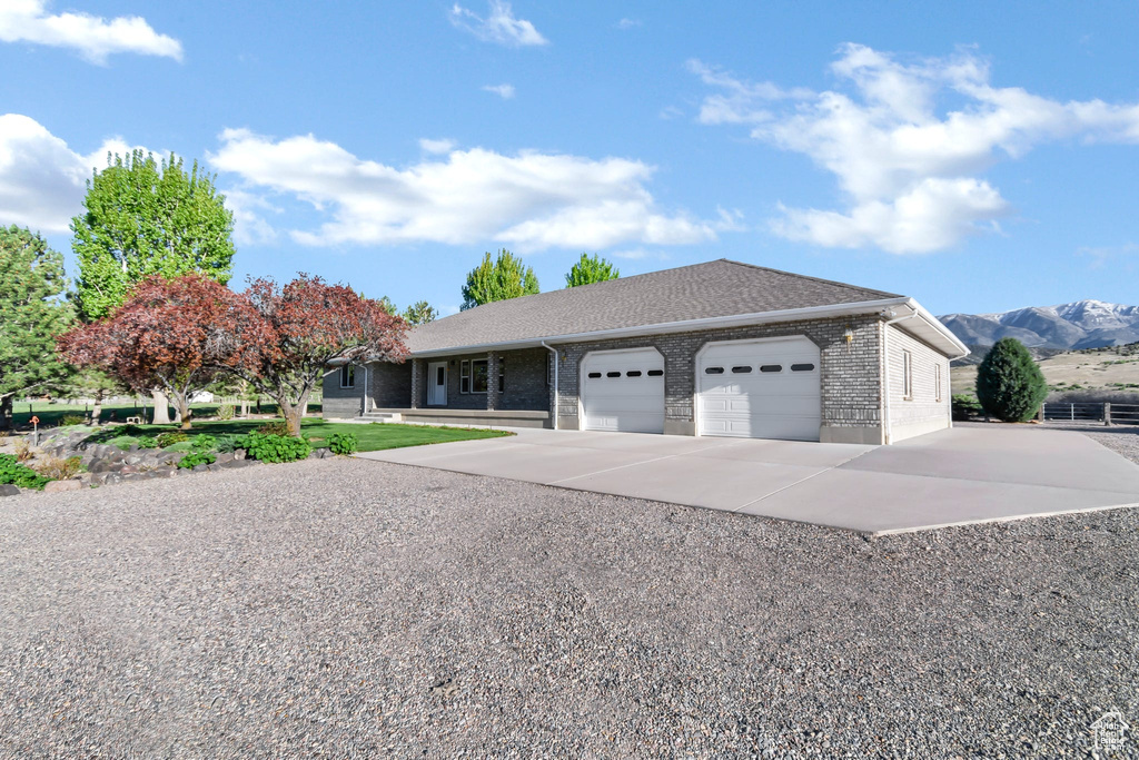 Ranch-style house with an attached garage, driveway, brick siding, and a mountain view