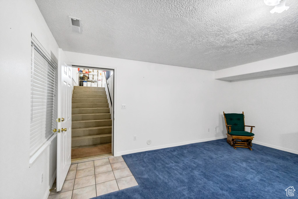 Unfurnished room with a textured ceiling, stairway, and baseboards