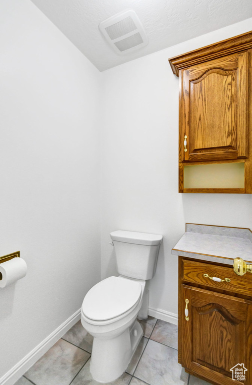 Bathroom with toilet, baseboards, and tile patterned floors