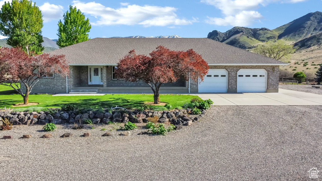 View of front of house with an attached garage, driveway, brick siding, and a mountain view