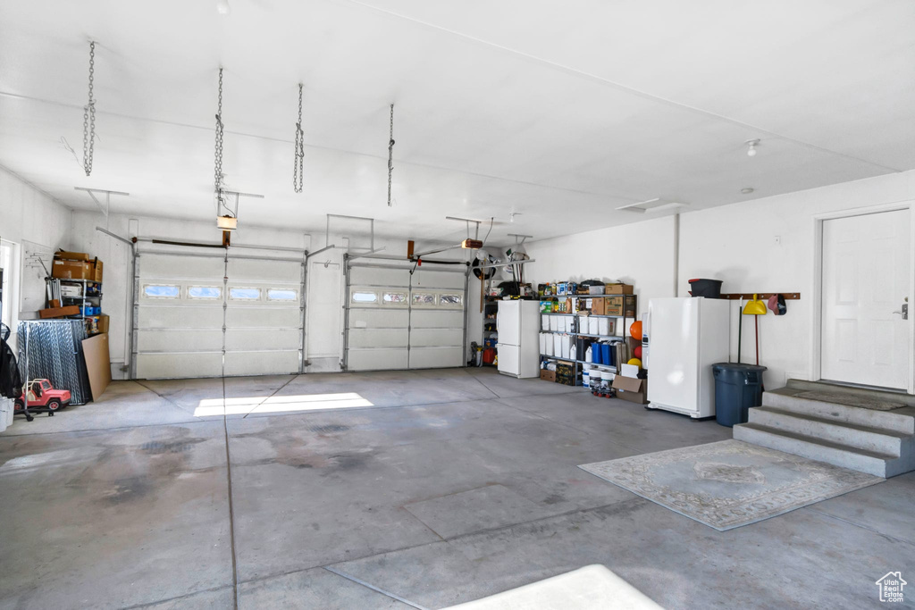 Garage featuring freestanding refrigerator and a garage door opener