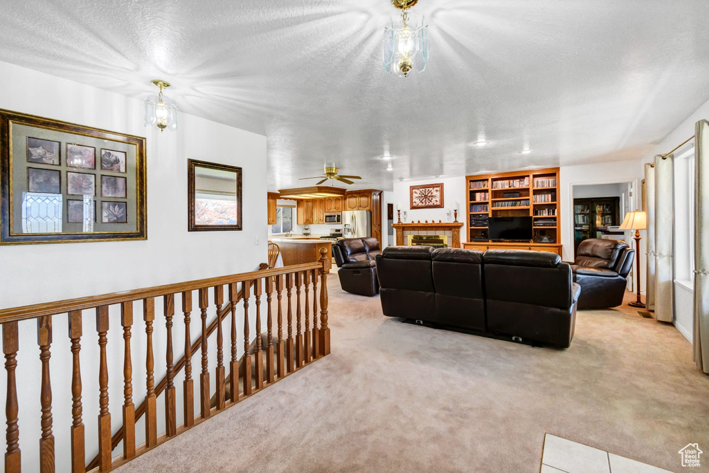 Living room featuring light colored carpet, a tile fireplace, a textured ceiling, and plenty of natural light