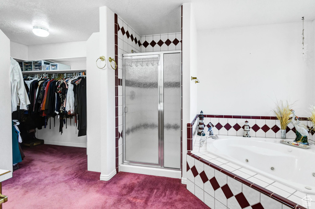 Full bath with a shower stall, a walk in closet, a tub with jets, a textured ceiling, and baseboards
