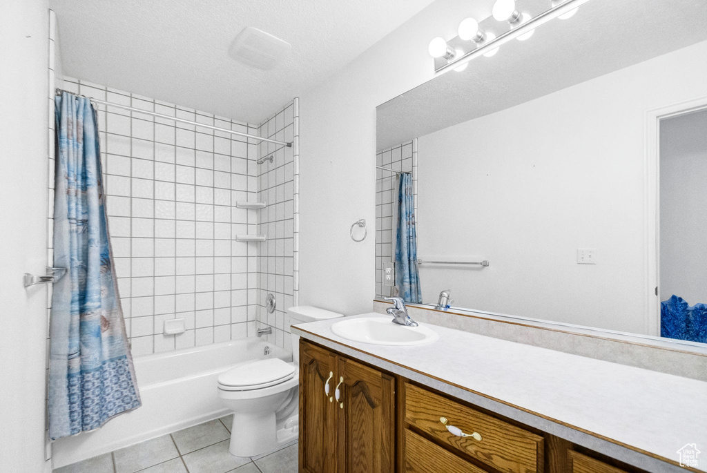Full bath with tile patterned flooring, vanity, toilet, and shower / bath combination with curtain