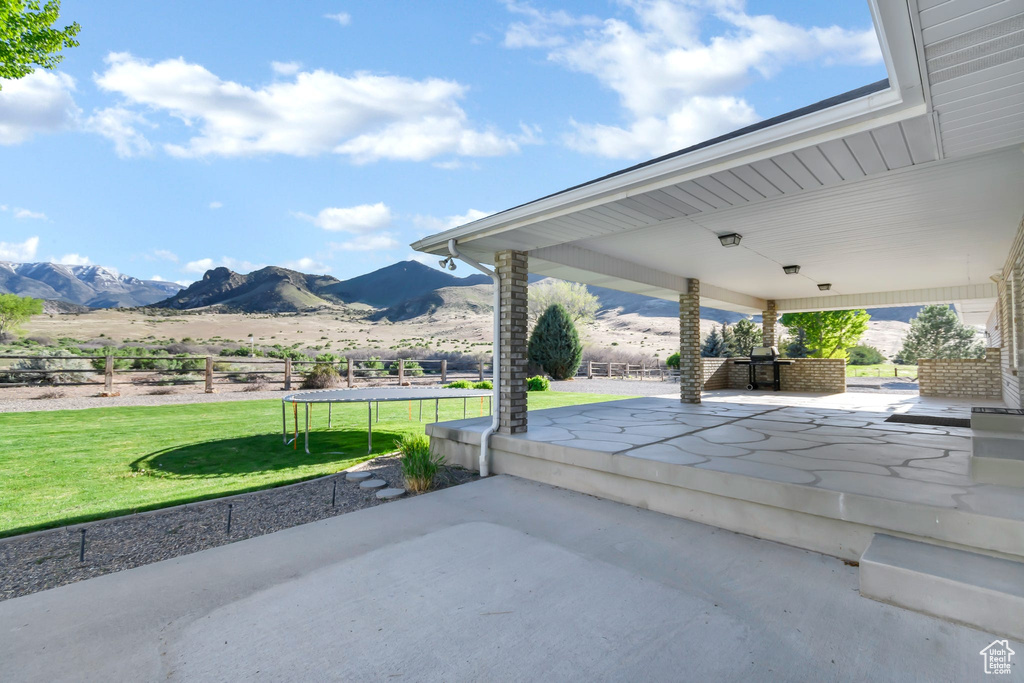 View of patio with a trampoline and a mountain view