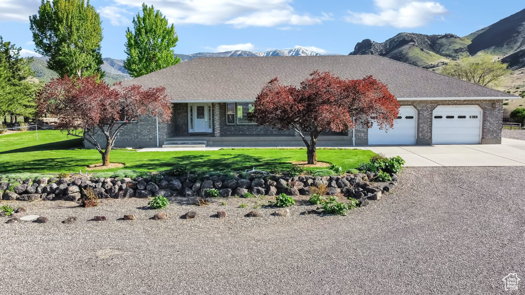 View of front facade featuring brick siding, a garage, a mountain view, and driveway
