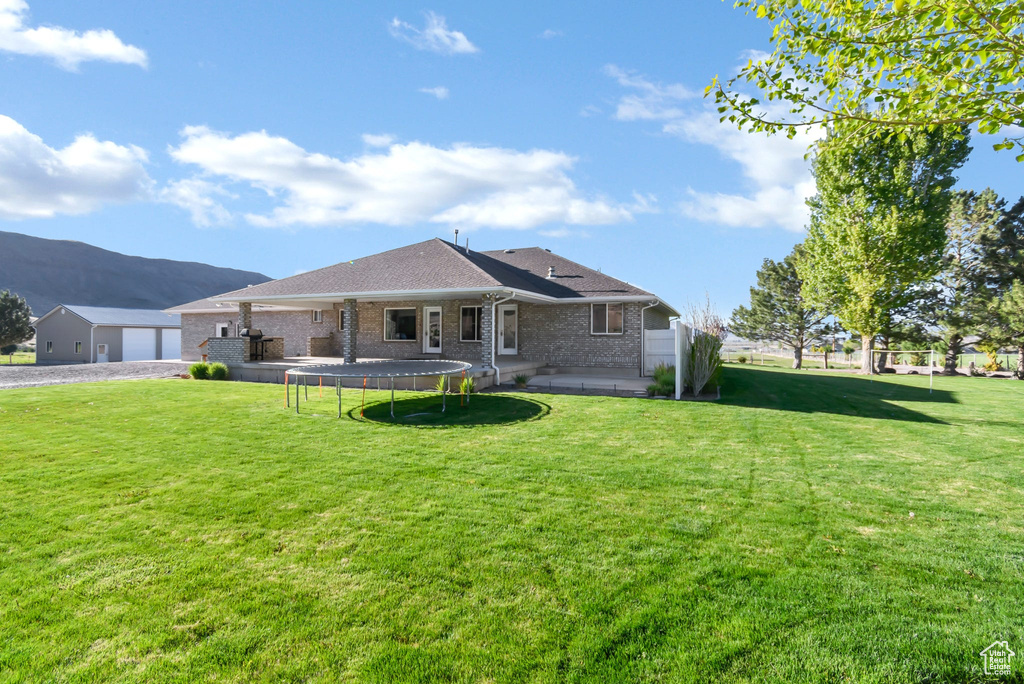 Rear view of property featuring a lawn, brick siding, a mountain view, driveway, and a shingled roof