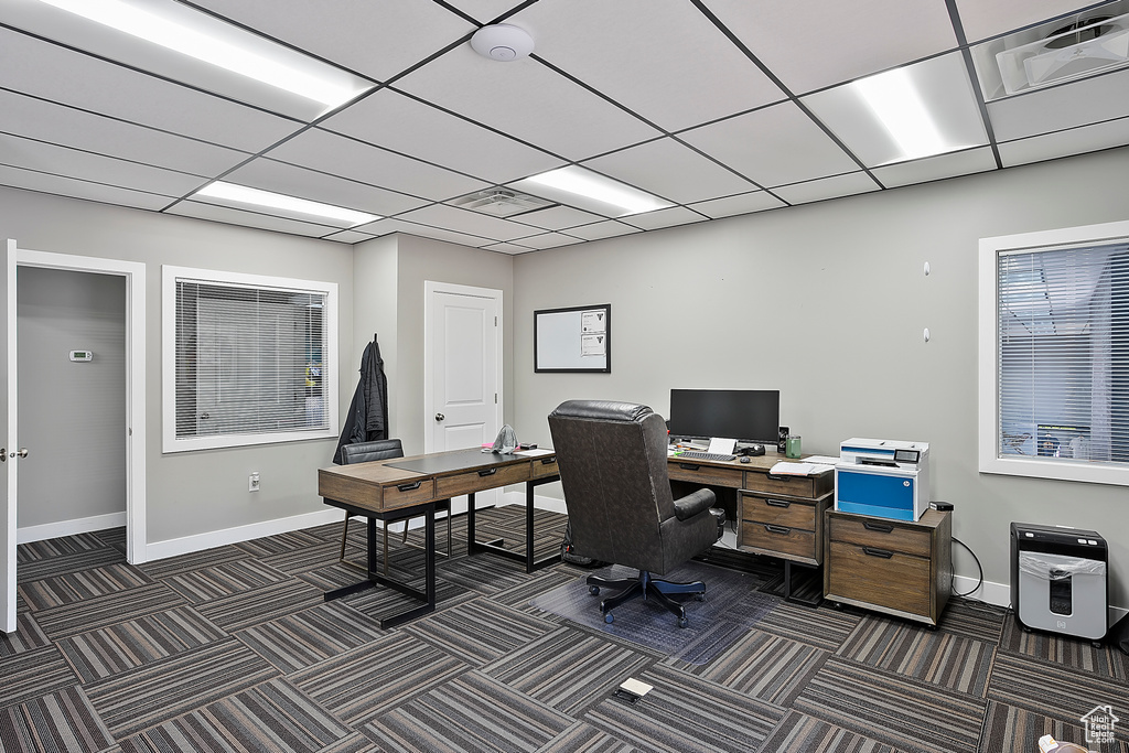 Home office featuring dark colored carpet, baseboards, and a drop ceiling