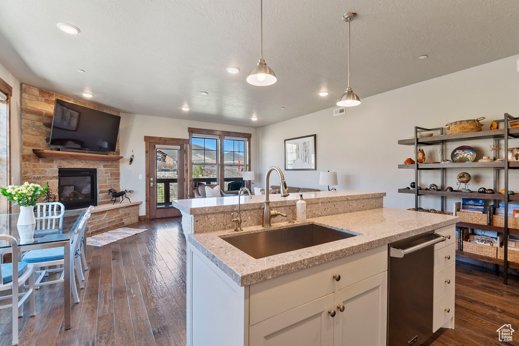 Kitchen featuring a sink, open floor plan, stainless steel dishwasher, decorative light fixtures, and recessed lighting