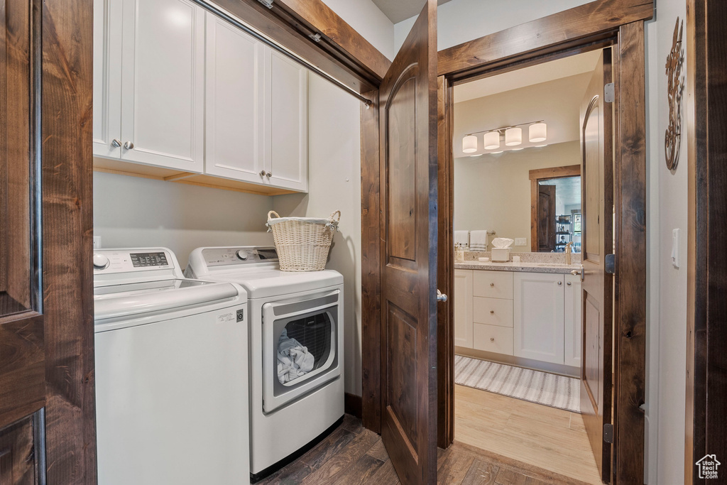 Clothes washing area featuring cabinet space, independent washer and dryer, and dark wood-style flooring