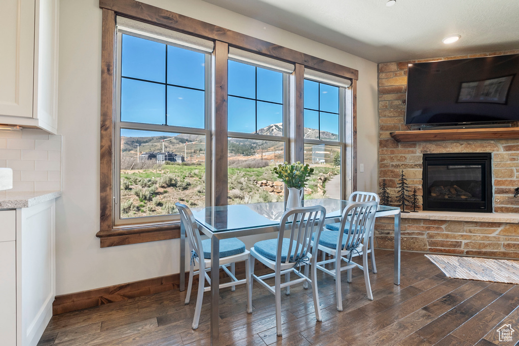Dining area featuring dark wood-style floors, baseboards, a fireplace, and recessed lighting