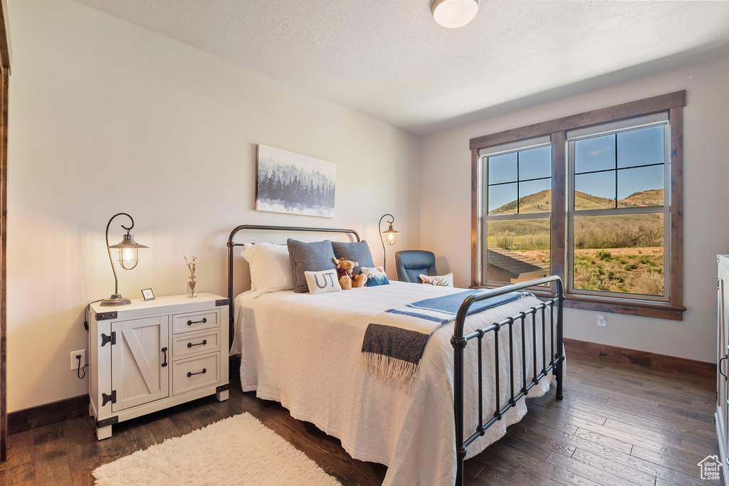 Bedroom featuring dark wood-style flooring and baseboards