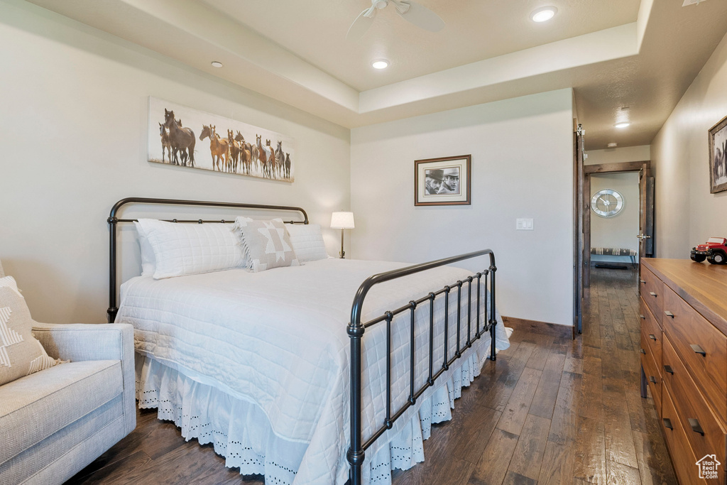 Bedroom featuring dark wood-style floors, recessed lighting, a raised ceiling, baseboards, and a ceiling fan