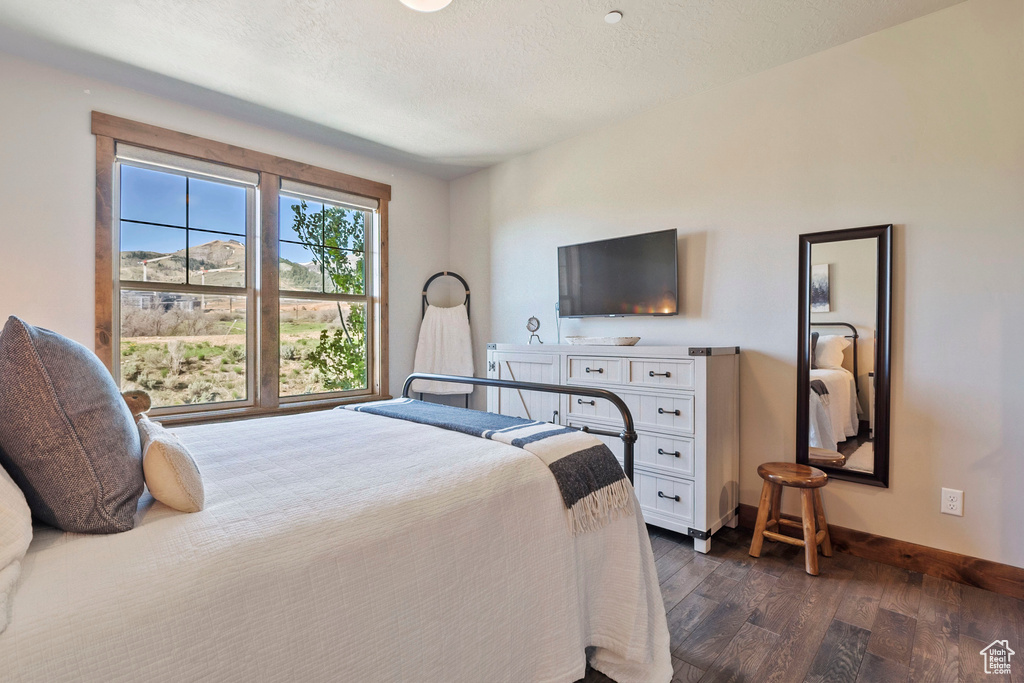Bedroom featuring dark wood-style floors and baseboards