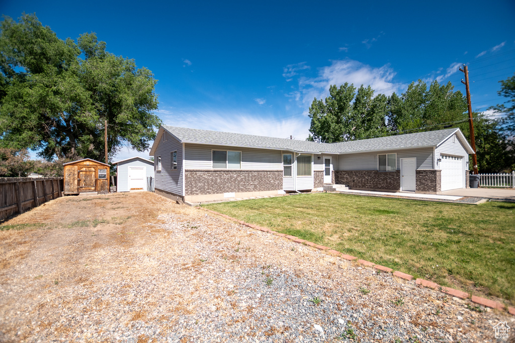 Ranch-style home with a storage unit, driveway, brick siding, and a garage