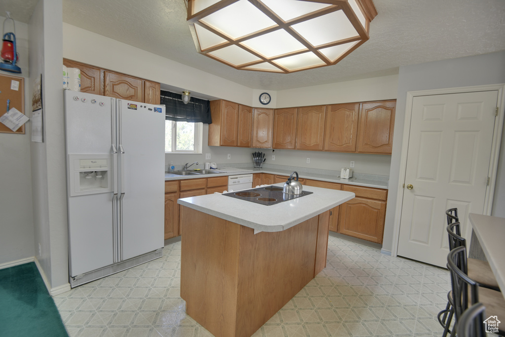 Kitchen featuring white appliances, light floors, light countertops, and a center island