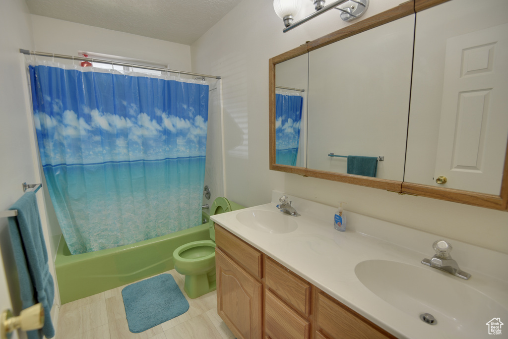 Bathroom with shower / tub combo, double vanity, and toilet