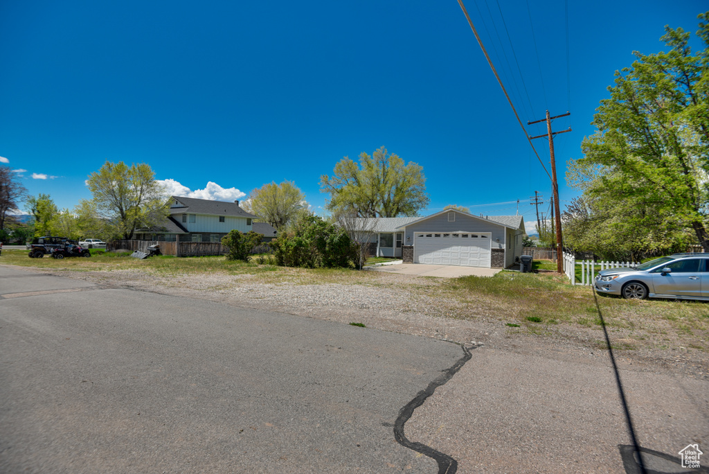 View of front of home with fence, a garage, and driveway