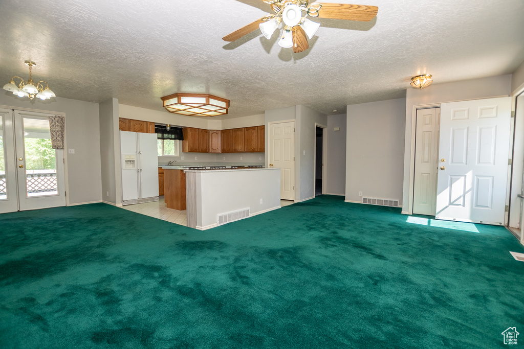 Kitchen with white refrigerator with ice dispenser, brown cabinetry, range hood, a center island, and a chandelier