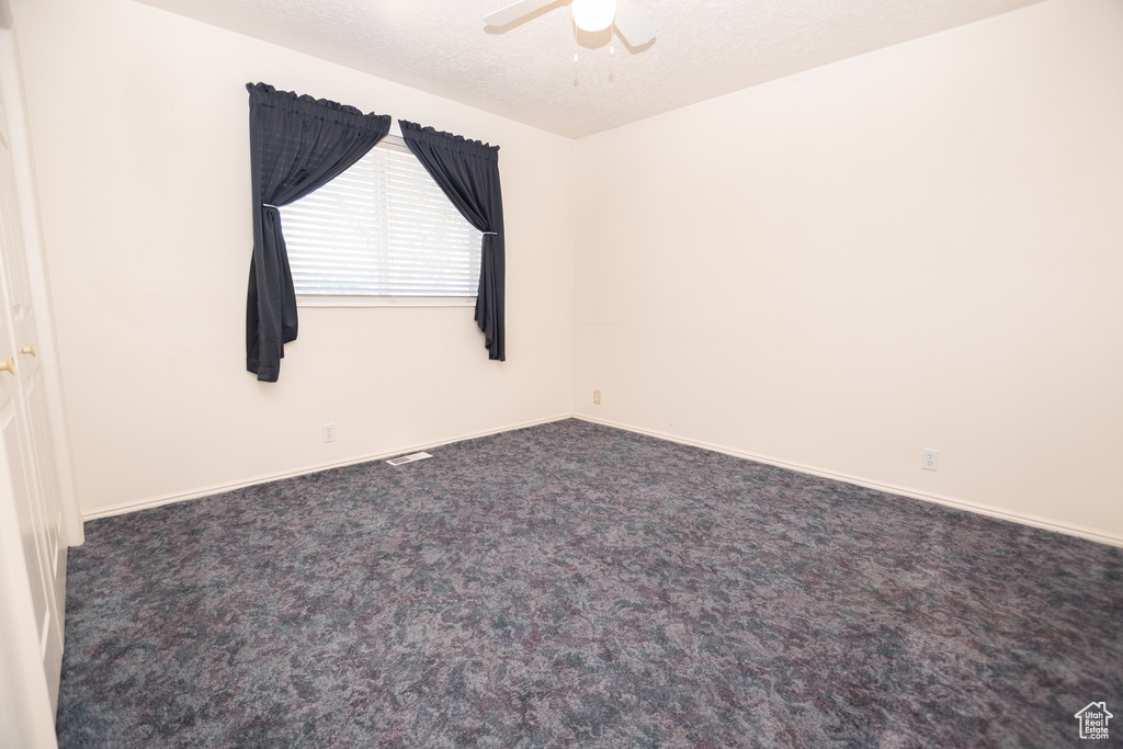 Empty room with a ceiling fan and carpet