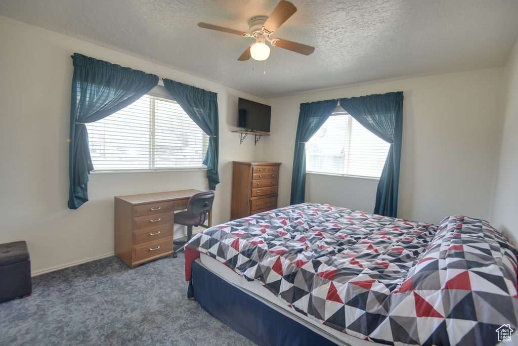 Carpeted bedroom with a textured ceiling and ceiling fan
