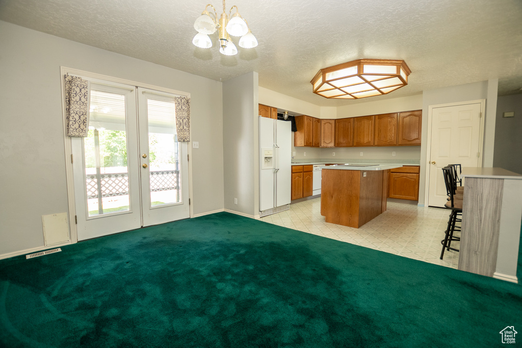 Kitchen featuring a kitchen island, a chandelier, french doors, brown cabinetry, and light countertops