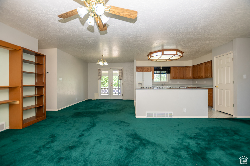 Unfurnished living room featuring a textured ceiling, a ceiling fan, french doors, and light colored carpet