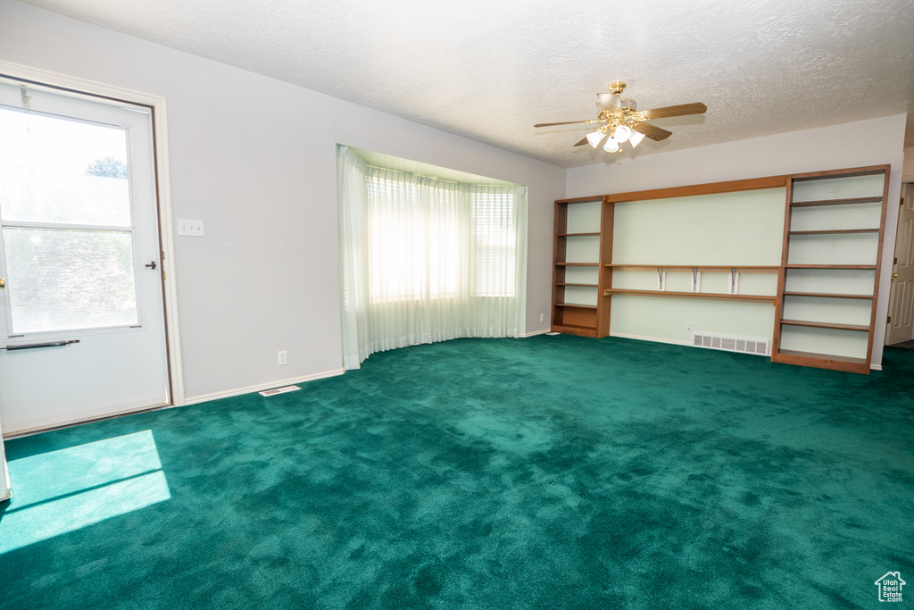 Unfurnished room with a ceiling fan, plenty of natural light, a textured ceiling, and carpet