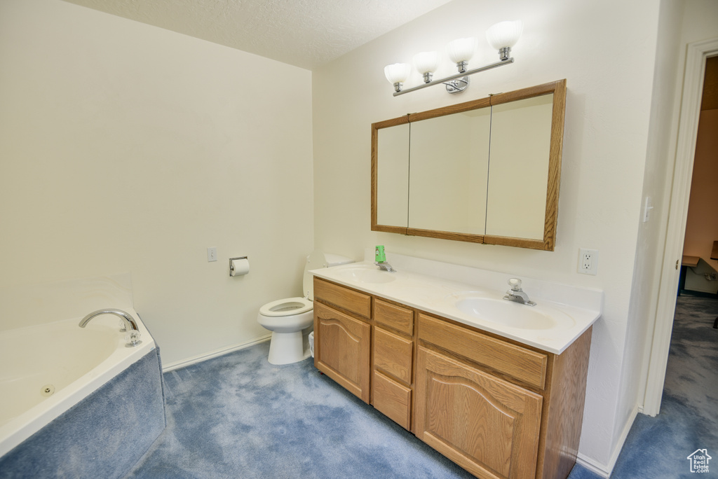 Bathroom featuring double vanity, a bath, toilet, and baseboards