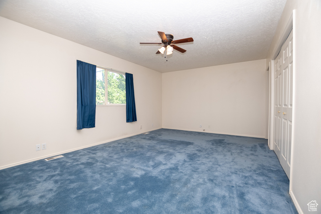 Unfurnished bedroom featuring a textured ceiling, carpet flooring, and a ceiling fan