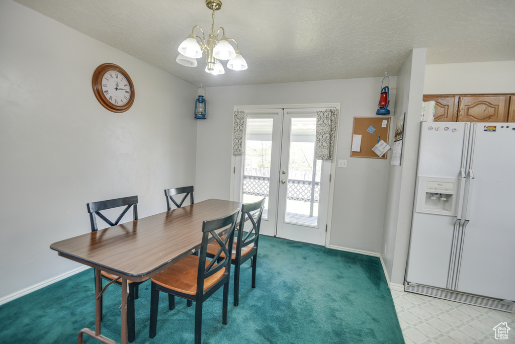 Dining area featuring a chandelier, french doors, baseboards, light colored carpet, and a textured ceiling