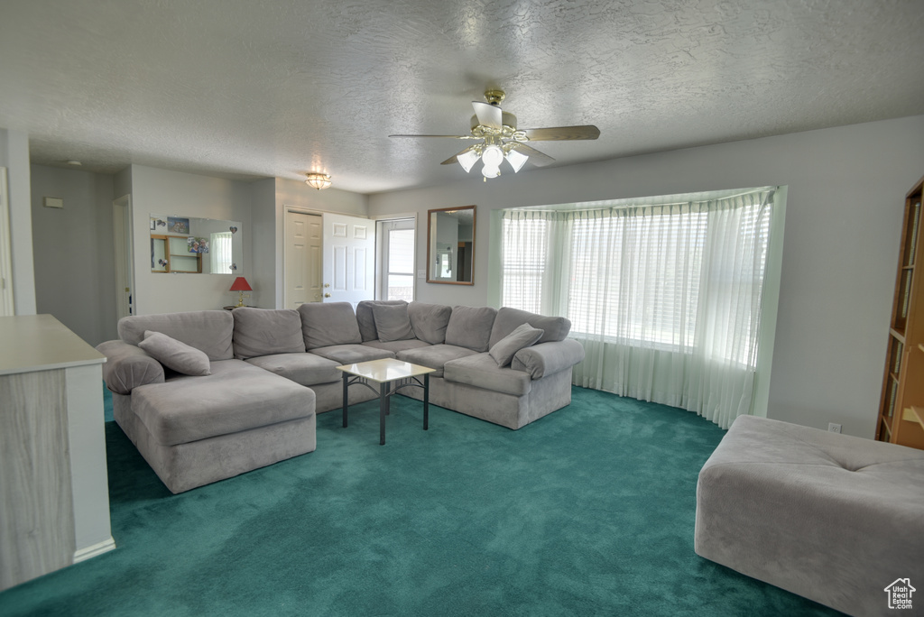 Living area featuring ceiling fan, a textured ceiling, and carpet floors