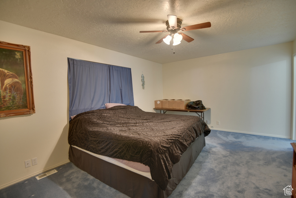 Bedroom with carpet floors, a textured ceiling, and ceiling fan