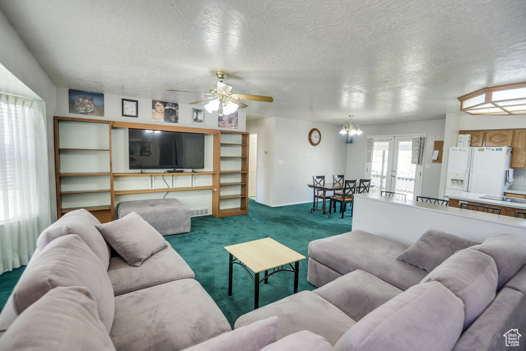 Living area featuring a textured ceiling, carpet flooring, ceiling fan, baseboards, and french doors