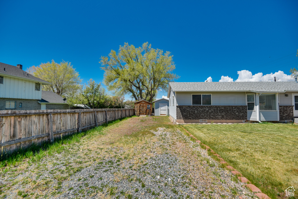 View of yard featuring a storage shed, an outbuilding, and driveway